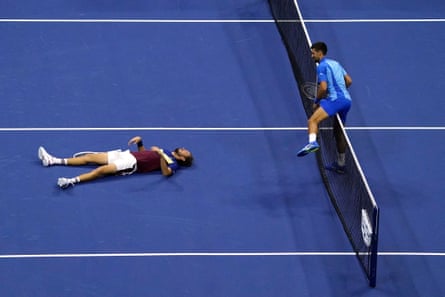 Novak Djokovic climbs over the net to check on Daniil Medvedev after he fell