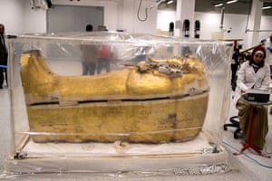An Egyptian archeologist works next to the gilded coffin of King Tutankhamun