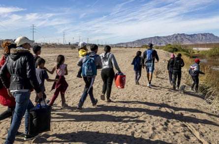People carrying bags and backpacks walk towards the river