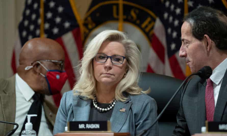Two men and a woman in the Capitol building in front of flags