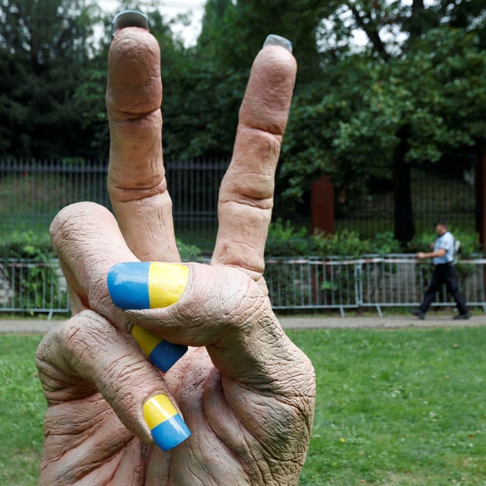 A police officer walks past a statue of a hand with fingernails painted in colours of Ukraine’s national flag in Prague, Czech Republic.