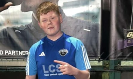 A boy wearing a football shirt points his finger