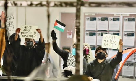 Pro-Palestinian protesters hold up signs while occupying a building on the campus of California State Polytechnic University, Humboldt, in Arcata, Calif., Monday, April 22, 2024. Students at the university used furniture, tents, chains and zip ties to block entrances to an academic and administrative building on Monday. University officials closed the campus through Wednesday. (Andrew Goff/Lost Coast Outpost via AP )