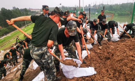 China’s paramilitary police officers reinforce a lake dyke following heavy rains which caused severe flooding near Zhengzhou city