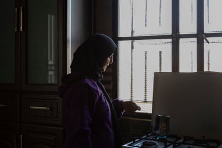 A woman in her headscarf in a dark room lit by a window