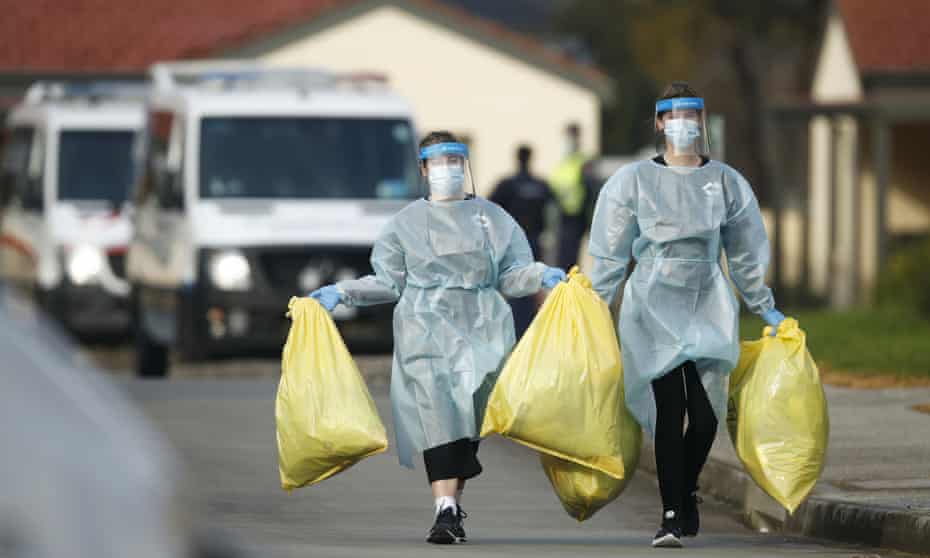 Two women in PPE with large full plastic bags