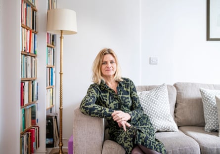 She sits on a grey sofa, leaning on one arm