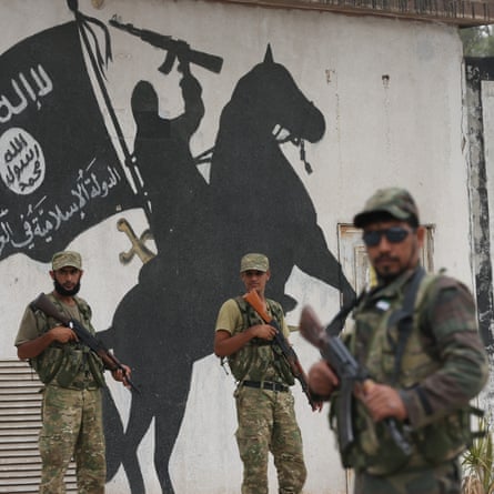 Members of Free Syrian Army stand in front of an Isis mural in Jarabulus.