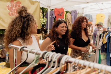 three women smiling and laughing next to racks of clothing