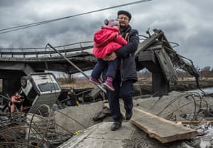 Russia-Ukraine war: Zelenskiy vows to ‘punish atrocities’ as family dies trying to evacuate Irpin – live | World news 4 Civilians cross the rubble of a damaged bridge in Irpin near Kyiv.