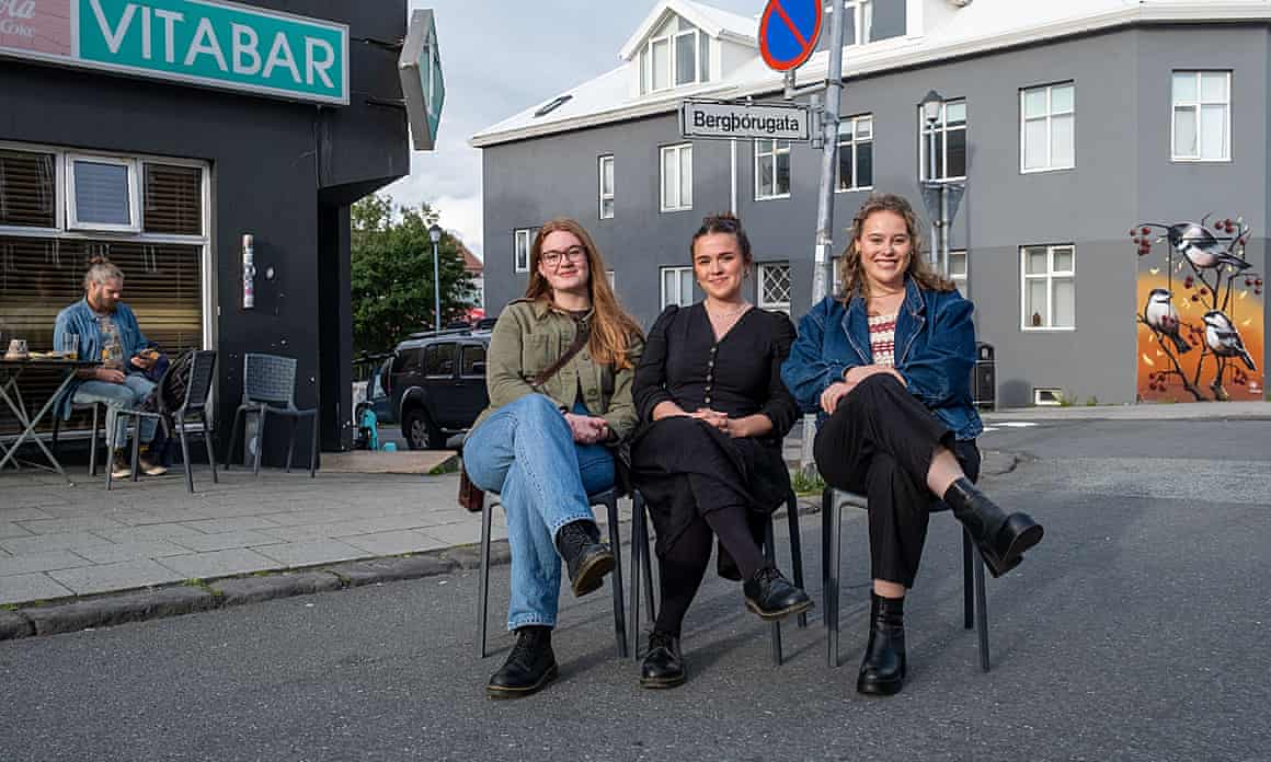 Three people sitting on chairs in the road