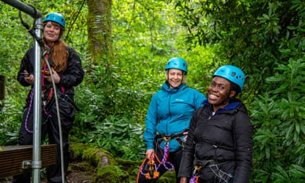 Three women in a forest preparing for a ride on a zip wire