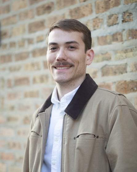 a man smiling as he stands in front of a brick wall