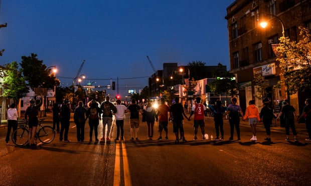 Protestors form a human chain in front of police officers near the 5th police precinct in Minneapolis