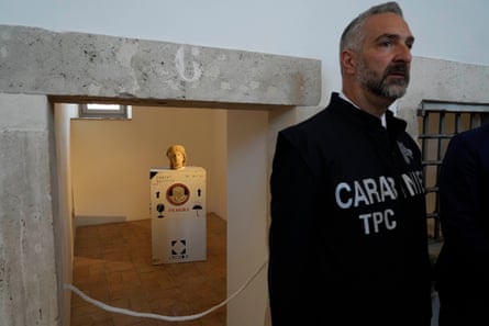 Man stands in front of roped off room with artifacts inside