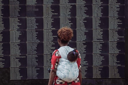 A woman carrying her baby on her back looks at the wall of victims’ names at the Kigali Genocide Memorial 