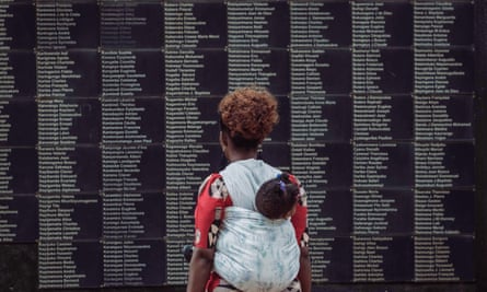 A woman carrying her child looks at the wall of Rwanda genocide victims’ names as a memorial in Kigali.