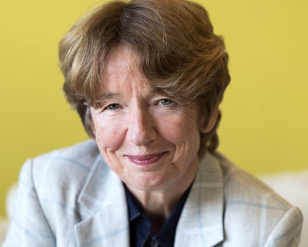 Dawn Airey in a suit jacket smiles in front of a yellow backdrop