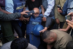 People in press flak jackets mourning at a funeral