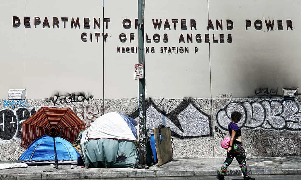 A person walks past a tent encampment set against the Department of Water and Power in Los Angeles.
