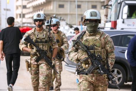 Three men in uniform walk through a street.