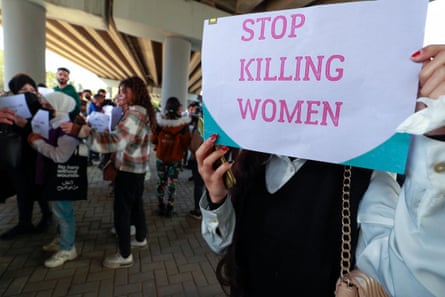 A woman holds a sign reading ‘Stop killing women’ at a protest staged under a flyover