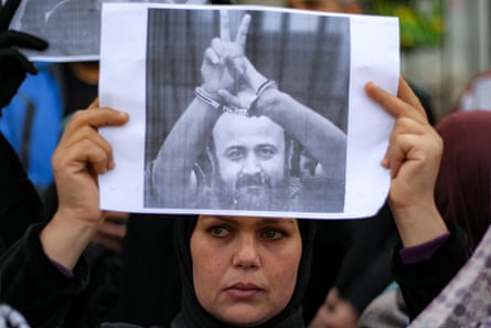 A woman holds up a printed picture of Marwan Barghouti