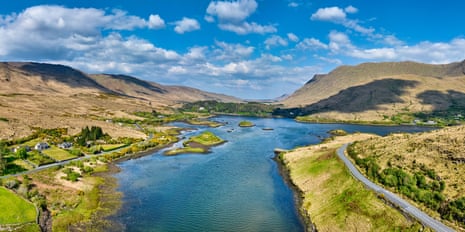 Killary Fjord winds between brown Connemara hills and green patches under a cloudy sky, with roads visible along the banks