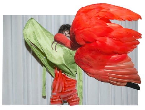 A child covering their face while holding large flamingo wings