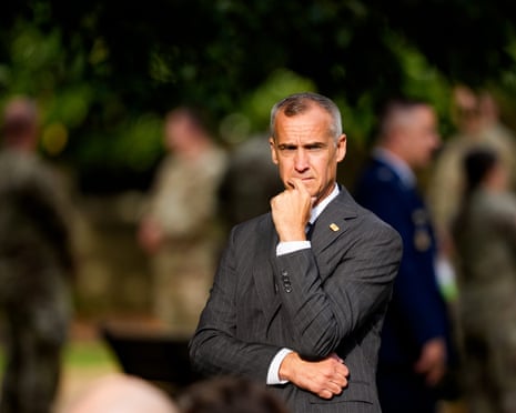 A man in a suit with arms crossed and one hand on chin.