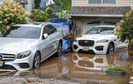 Three cars swept up on to a flooded driveway of a house