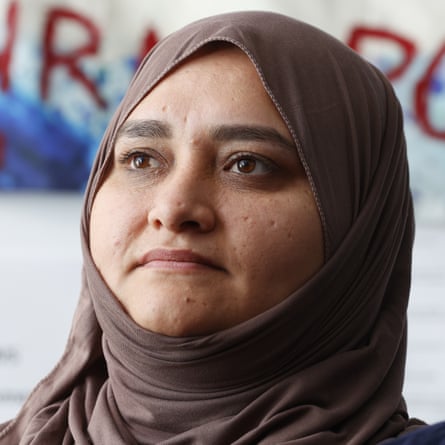Syeda, in a headscarf and in front of a cloth decoration, looking a bit serious