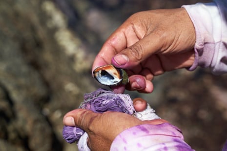 Close up of someone holding purple yarn in one hand and a snail in the other
