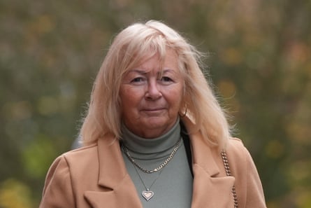 Spragg, with long hair, wearing a light brown jacket and a heart pendant