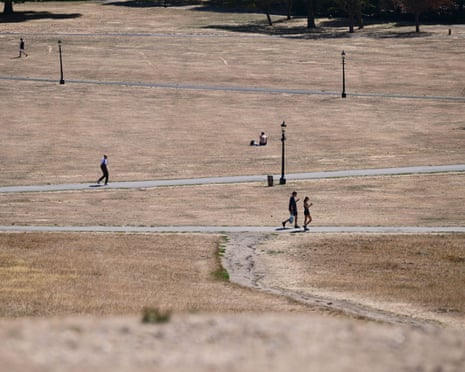 People walk across a sun-scorched brown lawn on Primrose Hill during a heatwave