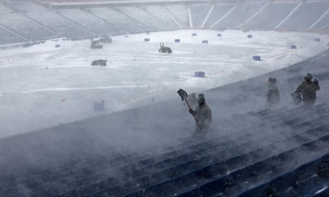 football stadium covered in snow where workers remove snow