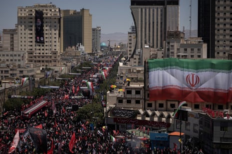 Aerial view of street filled with people waving flags and holding signs.