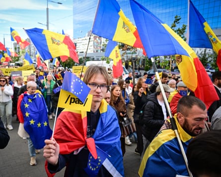 In a large crowd walking down a road, some people hold the Moldovan flag and some carry EU flags