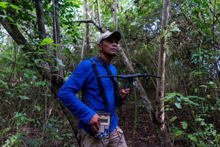 a man standing in a forest holding electronic equipment