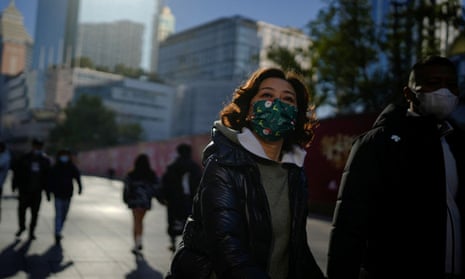 People wearing protective masks walk in a shopping district in Shanghai as China returns to work despite continuing coronavirus disease.