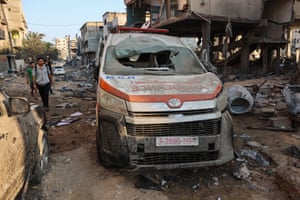Palestinians inspect the damage to buildings and an ambulance