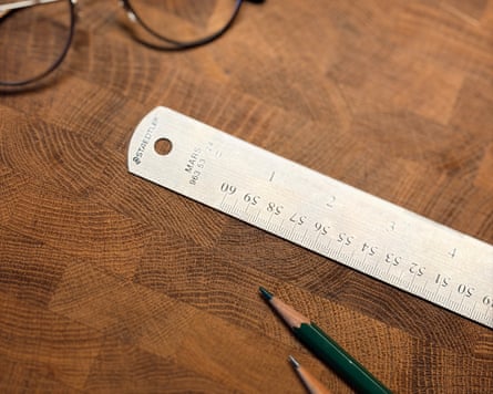 A Staedtler Stainless Steel Metric Ruler alongside pencils and a pair of glasses