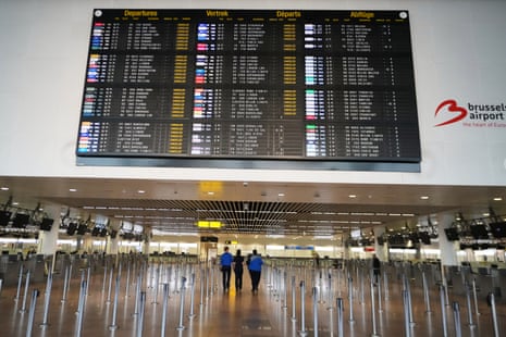 Employees walk through an empty terminal with a departure board of cancelled flights at Brussels international airport in Zaventem, Belgium, on Tuesday.