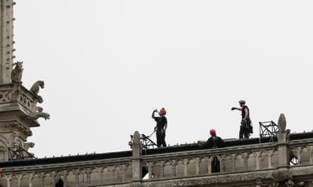 Workers stand on top of Notre Dame Cathedral