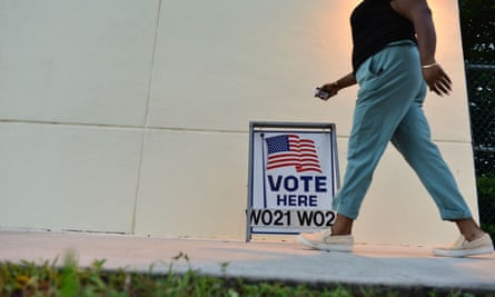 person walks by ‘vote here’ sign