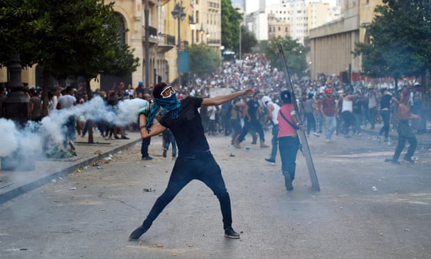 An anti-government protester throws a teargas canister back towards riot police during a clash with security forces in the area close to the parliament in Beirut.