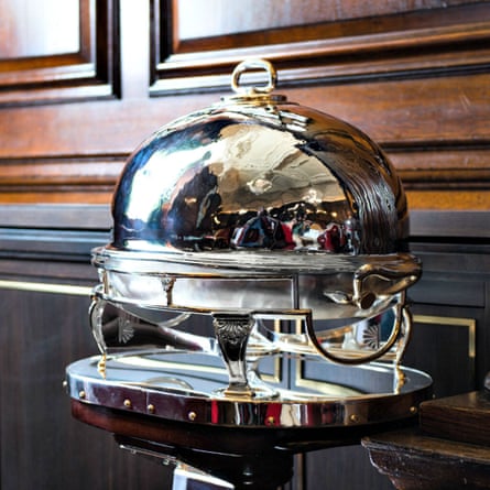 A silver cloche rests beside a panelled wood wall