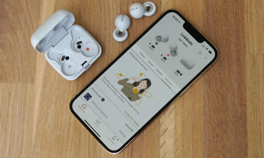The Headphones Connect app on an iPhone on a table next to the LinkBuds and open charging case.
