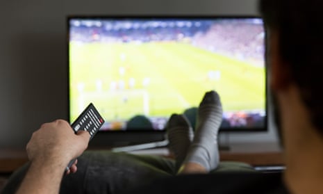 Man watching football on tv sitting on a couch.