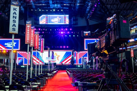 A red carpet leads a stage with a stars and stripes backdrop, flanked by signs naming the different state delegations present at the convention